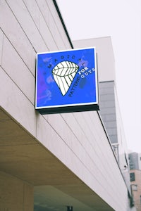 a sign with a diamond on it hanging from the side of a building